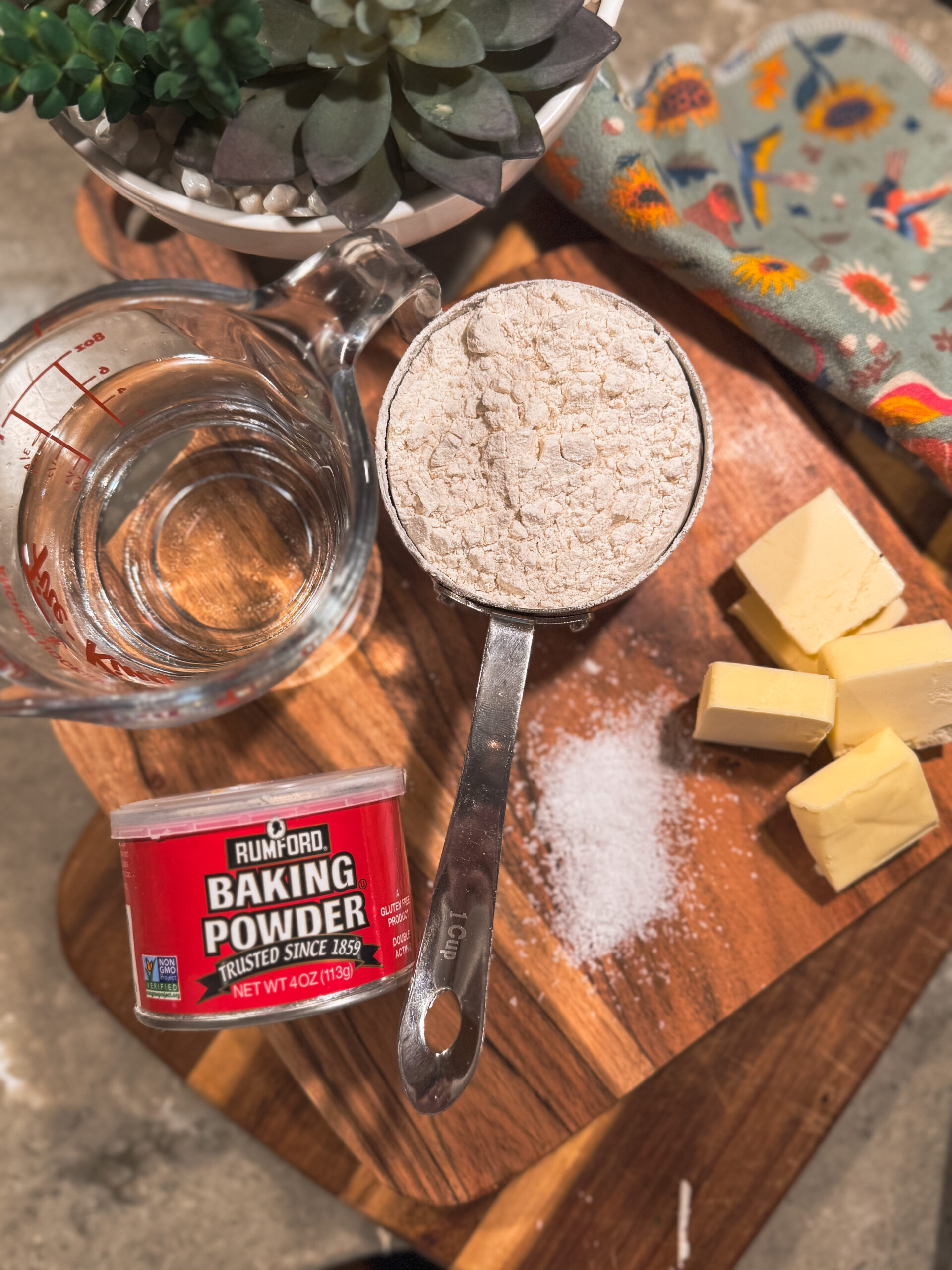 a measuring cup with flour and butter on a cutting board