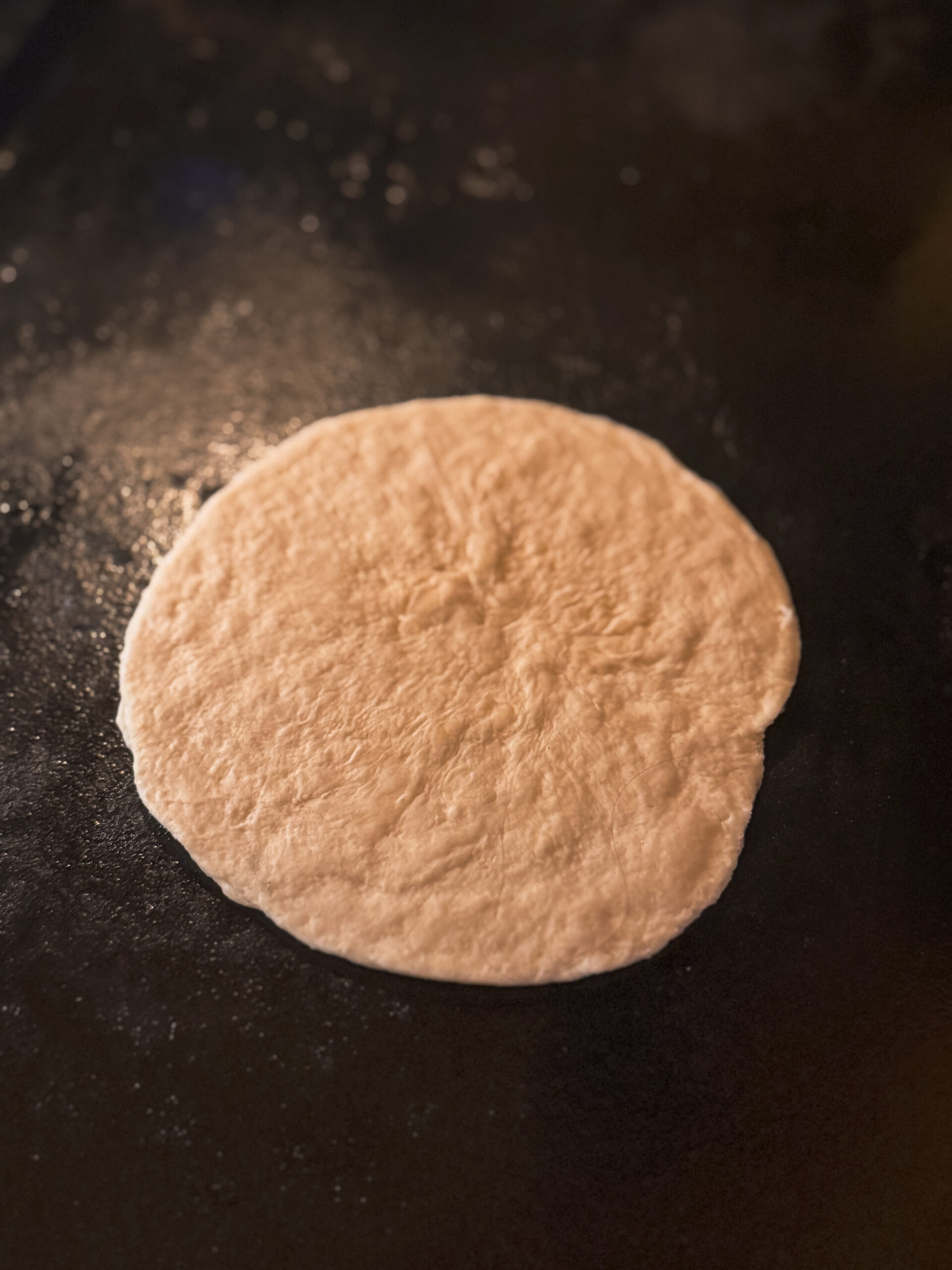 a round white dough on a black surface