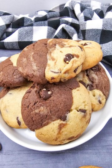 Close-up of a white dish stacked high with brookies recipe cookies showing the distinct brownie and cookie dough halves baked together.