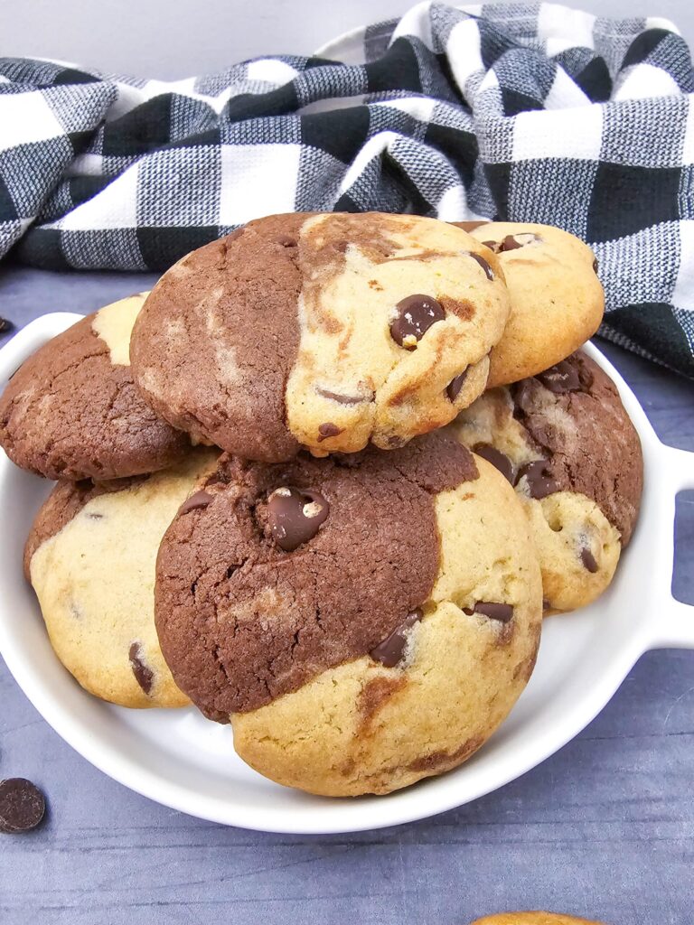 Close-up of a white dish stacked high with brookies recipe cookies showing the distinct brownie and cookie dough halves baked together.