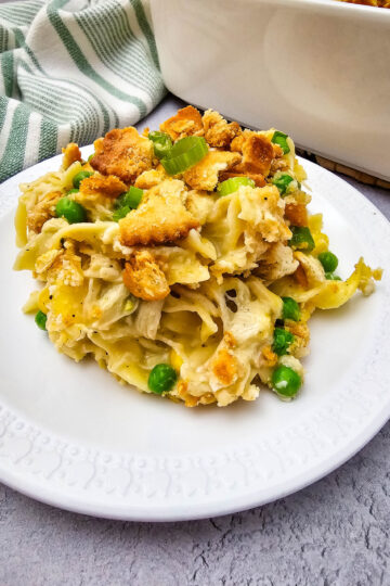 Close-up of creamy Chicken Noodle Casserole with egg noodles, shredded chicken, peas, green onions, and buttery cracker crumbs.