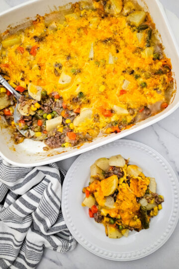Hobo Casserole with ground beef, potatoes, mixed vegetables, and melted cheddar cheese served from a baking dish.