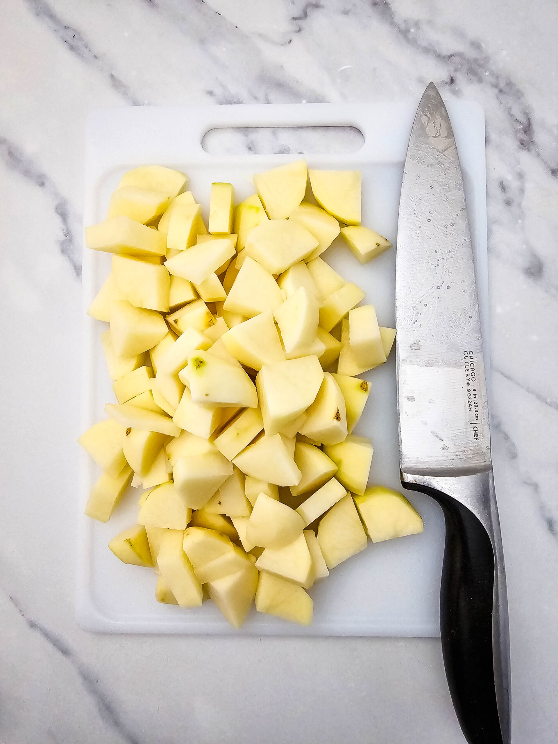Diced potatoes on a cutting board with a knife for making Hobo Casserole.